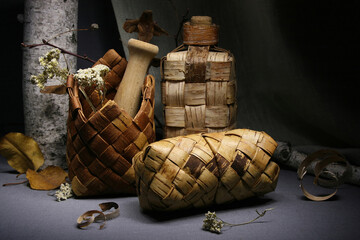 Birch bark products. Still life with a wicker bottle, napkin holder and pencil case.