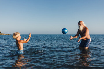 Grandpa and Grandson Playing with Ball in the Sea