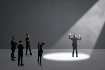 Fototapeta premium Businessperson under spotlight with others observing in dark grey background. Concept of career choice, ambition, and success.