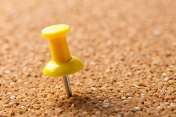 Macro Close-up of Yellow Push Pin on Corkboard Texture