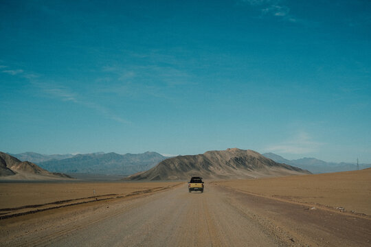 Rear view of an off road vehicle driving along a dirt road in remote wilderness landscape, Chile