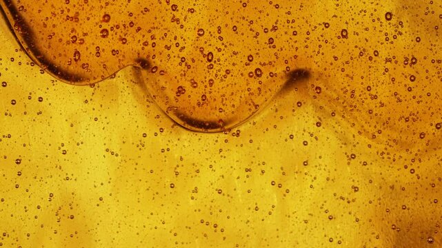 Close-up slow motion shot of pouring yellow caramel or fresh honey with air bubbles, seamless dripping sweet liquid syrup drip flows, thick organic honey dripping, golden caramel sauce flowing