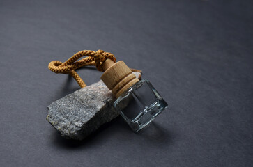 Bottle with liquid and gray stone. Black background.