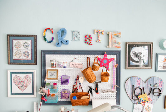 The word create over a Mood board hanging on the wall of an art studio with assorted pictures and craft objects
