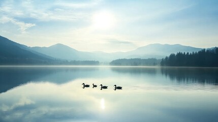 Fototapeta premium Serene lake scene with ducks and mountains under a soft, misty sky.