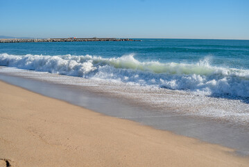 Waves and foam on the beach in Barcelona. The beach of the Mediterranean Sea.