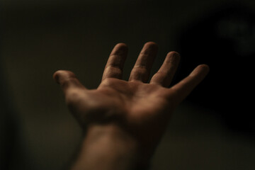 Close-up personal perspective of an outstretched hand against a black background
