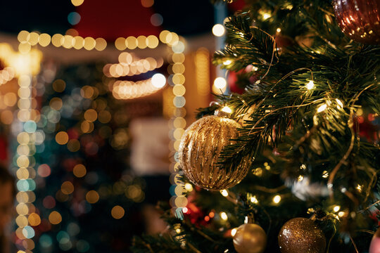 Close-up of Christmas baubles and illuminated string lights on a Christmas tree outside a building