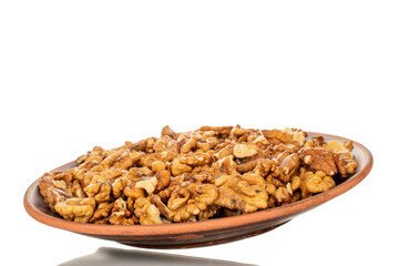 Shelled walnuts on a clay plate, close-up, isolated on a white background.