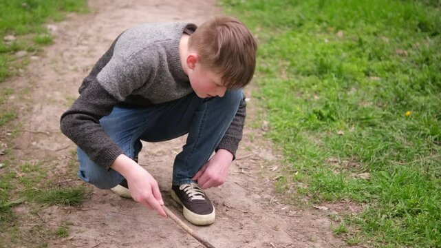 Happy boy playing in the woods looking for insects. outdoors activity. Summer holidays in city park