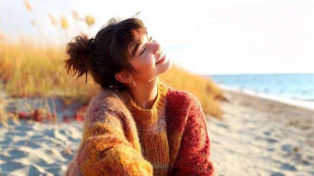 Woman smiling in sunlight wearing knit sweater in autumn field. Lifestyle and fashion content
