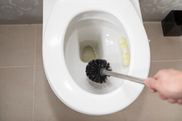 Сlose-up shot of a man cleaning a toilet using a special cleaning product and a brush	