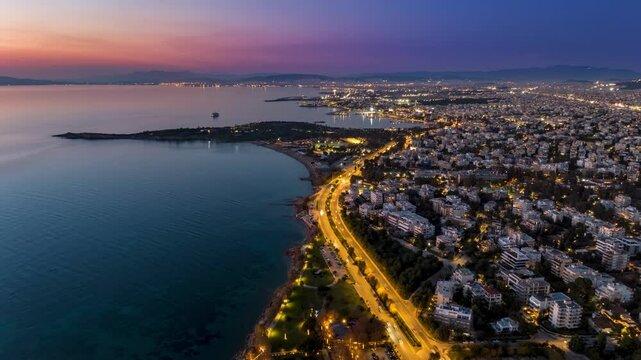 Aerial hyper lapse view of the illuminated Athens Riviera coast in Voula and Glyfada during dusk, Greece