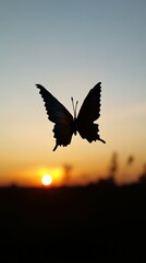Fototapeta premium A butterfly silhouette gracefully flying against a stunning sunset backdrop, capturing the beauty of nature and tranquility.