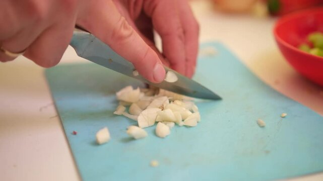 close up of unrecognizable male hands chopping garlic on board. Man's hands cutting garlic with a knife over cutting board. Making food at home, homemade