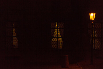 In the dark of night, the glowing windows of historic buildings in a European old town create a captivating scene. The soft light highlights the intricate details of the architecture. 