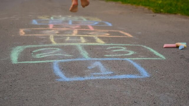 Children jumping hopscotch on the asphalt. Selective focus.