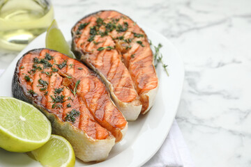 Tasty grilled salmon steaks with thyme, dill and lime on white marble table, closeup. Space for text