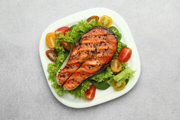 Tasty grilled salmon steak and vegetables on light grey table, top view