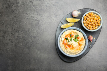 Delicious hummus with paprika and chickpeas served on dark grey table, flat lay. Space for text