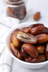 Tasty sweet dried dates in bowl on white table, closeup