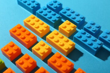Construction toy. Colorful building bricks on light blue background, closeup