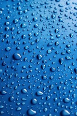 Droplets glisten on a smooth blue surface, creating a serene and refreshing visual effect