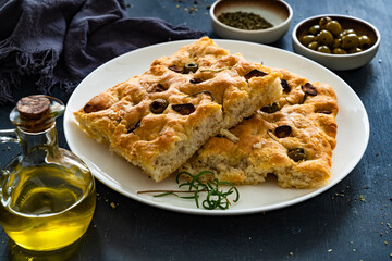 Focaccia alle olive - foccacia with green olives, garlic and rosemary on black background