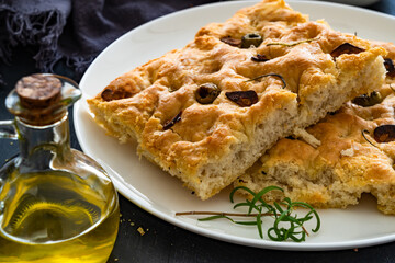 Focaccia alle olive - foccacia with green olives, garlic and rosemary on black background