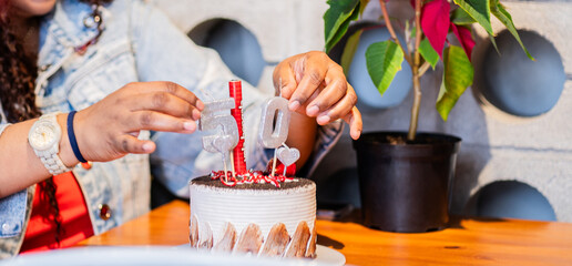 primer plano de manos ubicando los números en el pastel de cumpleaños  