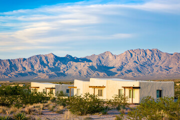 weathered adobe village houses with wooden beams at golden hour, desert mountains backdrop
