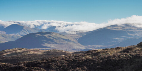 View from the top of Gowbarrow Fell with clouds cascading over the high fells, Lake District, UK