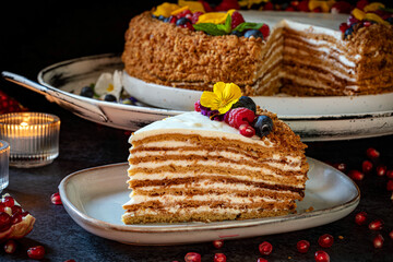 Medovik. Honey cake made from honey cakes with whipped sour cream, decorated with berries, pomegranate and flowers.
