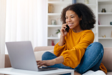 Remote Communication. Smiling Black Female Freelancer Talking On Cellphone Working On Pc At Home Office, Positive Lady Using Computer Having Phone Conversation, Enjoying Distance Job. High quality