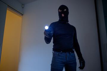 Burglar wearing a balaclava holding a flashlight
