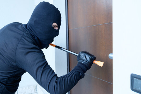 Burglar trying to force a door lock using a crowbar