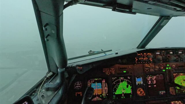 Captain pilot cockpit view landing aircraft in storm, rain, bad weather conditions on runway