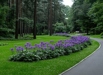 Colorful purple flowers line a winding pathway through a serene park filled with lush green trees and vibrant foliage during a quiet afternoon
