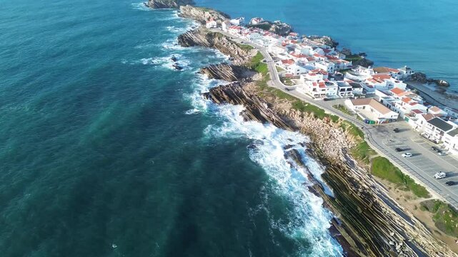 Drone footage of a seascape with Baleal Island with large waves and rocky cliffs