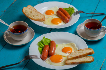 Breakfast for two fried eggs with sausages toast and tea in cups