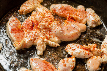 chicken fillet fried in spices and oil in a frying pan