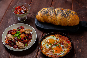 Jewish food shakshuka tzimmes with beans and dried fruits and fresh challah on the table. Horizontal photo