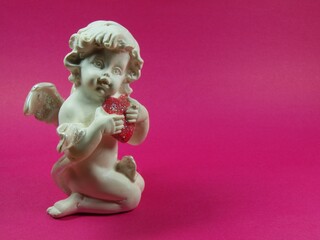 A white angel hugs a heart. Figurine. Love, greeting card. Invitation.
