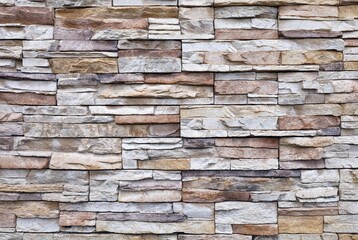 External wall coating made of  stacked bricks of  yellow, brown and white rocks. Stoneware panels...