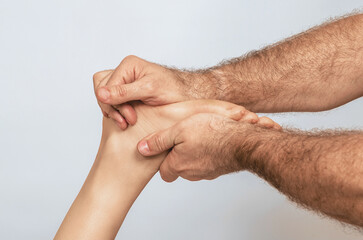 Fototapeta premium Male strong hairy hands embrace female toes and heel. Male hands do foot massage. Gray background.