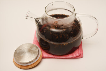Glass teapot with wooden lid on a white background. A teapot with a teapot inside.