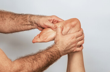 Fototapeta premium Finger pressure on foot, reflexology. Woman receiving foot massage. Spa center, gray background.