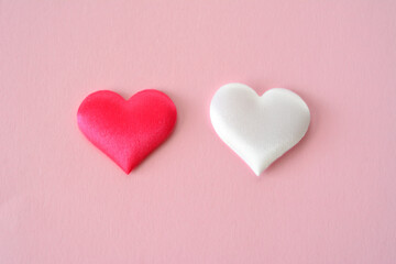 a red and a white silk hearts on the pink background