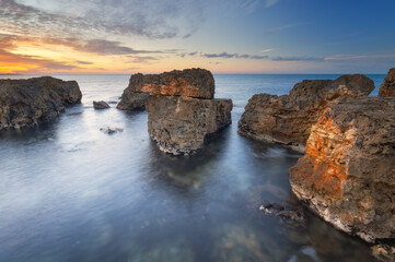 Beautiful nature seascape of beach shore among rocks on evening sunset.