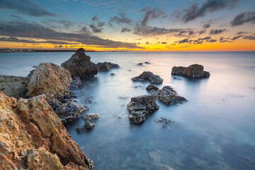 Beautiful nature seascape of beach shore among rocks on evening sunset.